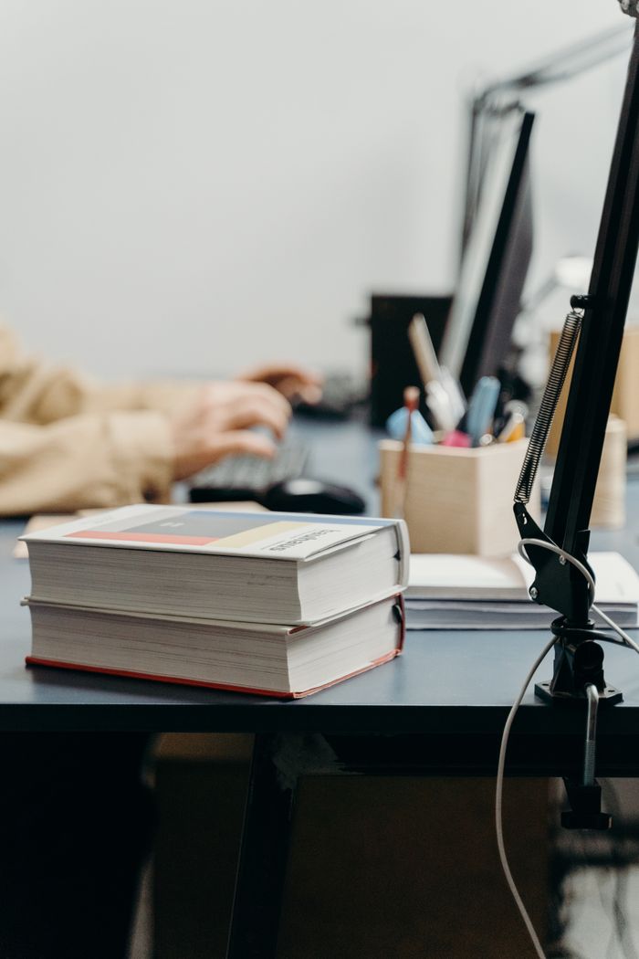The Art of Drawing Readers In: Your attractive post title goes here A warm workspace with books, computer, and person working, perfect for studying or remote work.